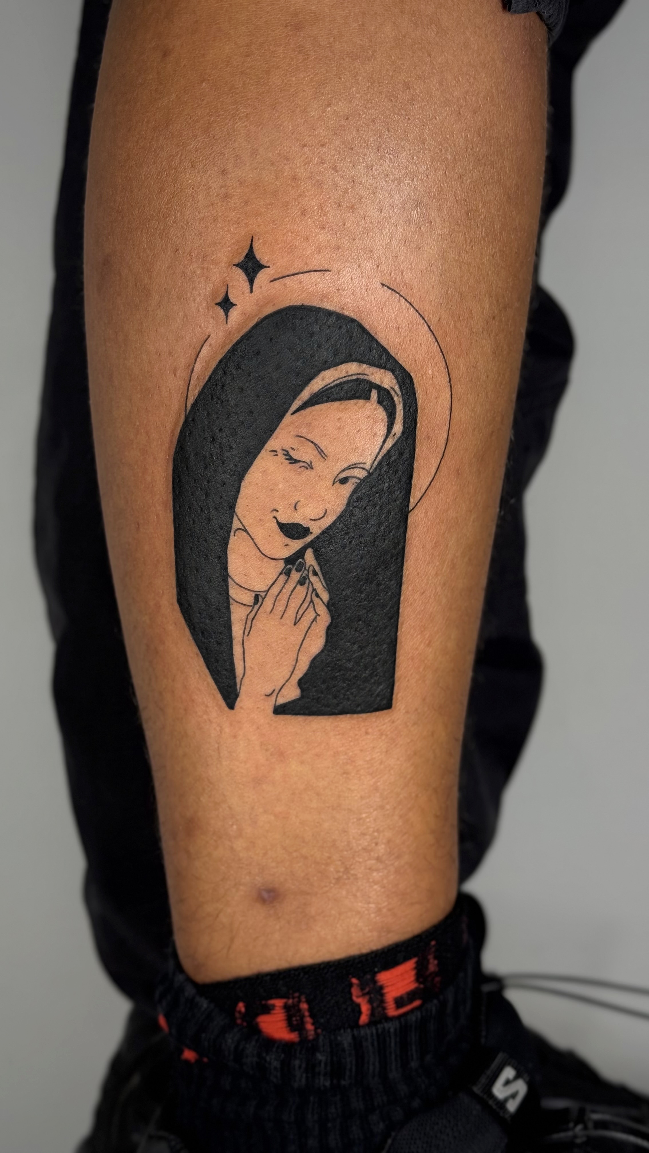 Blackwork Madonna tattoo on dark skin, calf placement — bold illustrative religious iconography in fine line and graphic style by Jane Again Tattoo, Mexico City. Blackwork on black skin specialist.