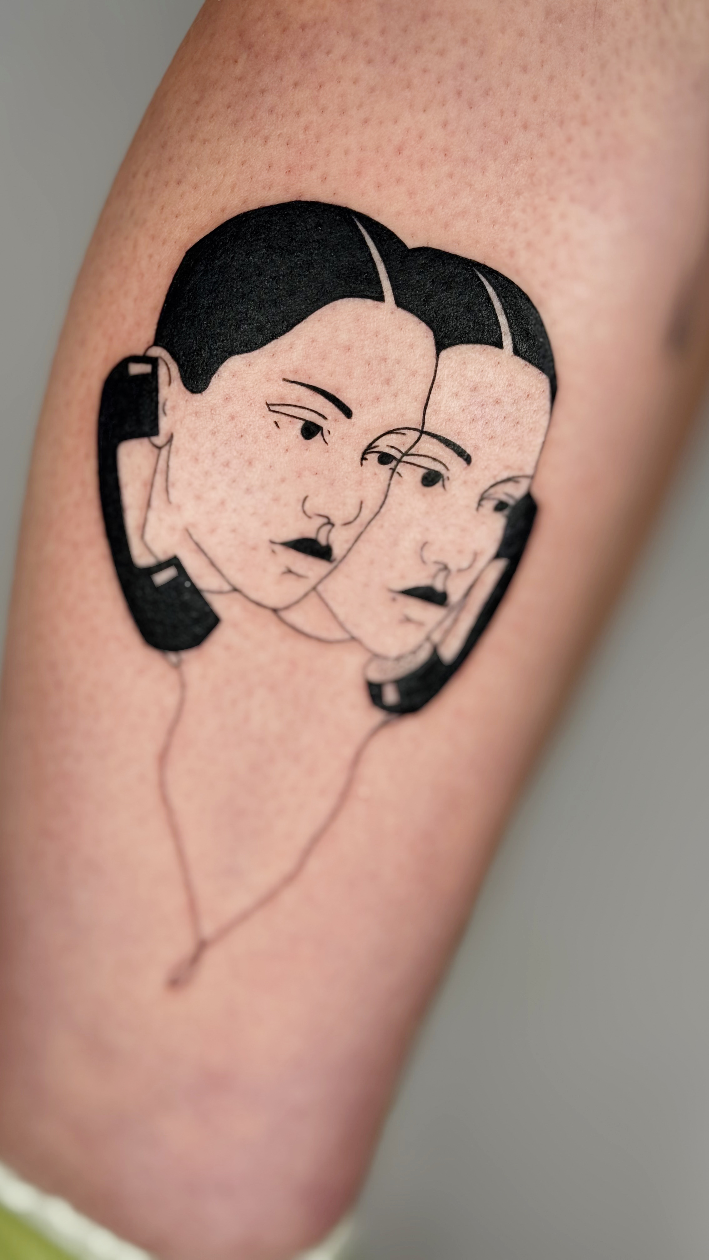 Blackwork tattoo of two overlapping women faces on the calf — fine line work illustrative portrait with bold graphic shapes by Jane Again Tattoo, Mexico City.